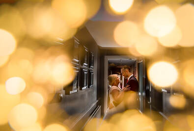 Couple hugging in corridor with yellow front bokeh effect of fairly lights in the foreground.